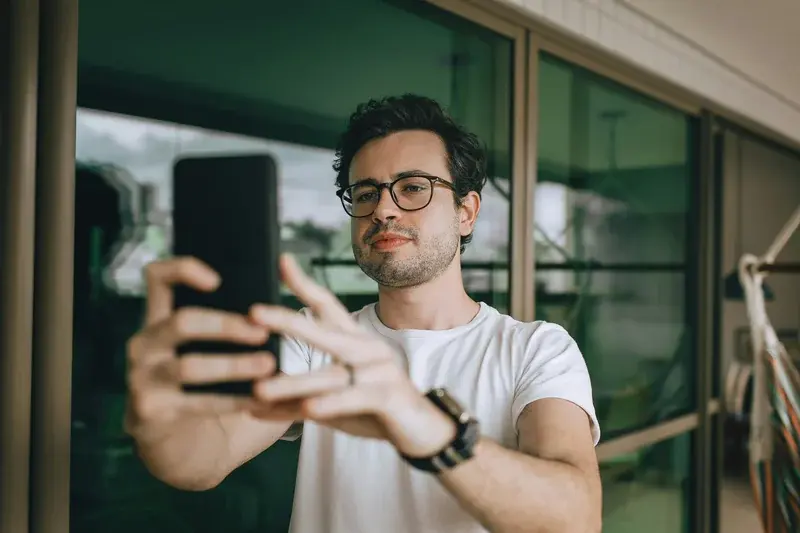 Man taking pictures of glasses with phone on balcony