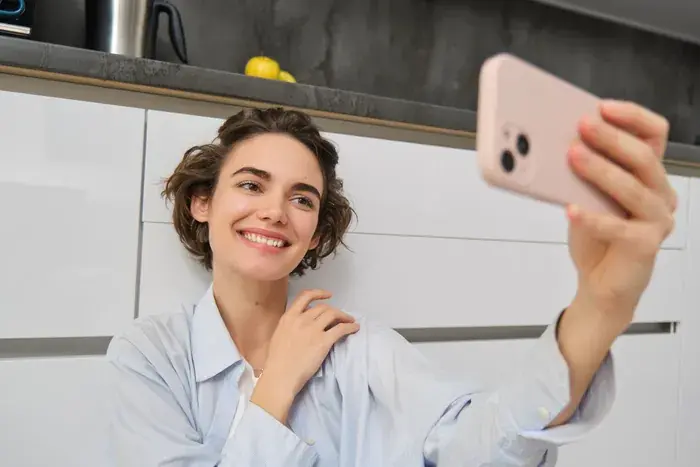 woman sitting down taking a selfie on her phone